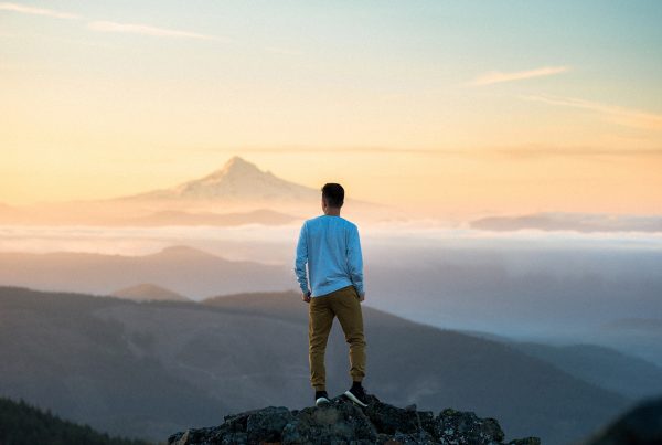 Financial Planet Article - There's something wrong with our industry. Man standing at the top of a mountain looking at the horizon
